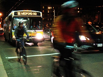 Bike riders and buses at night along Massachusetts Avenue