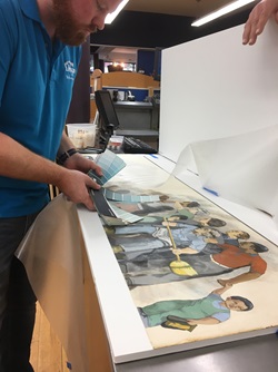 A conservator compares color samples with a printed copy of Bernard Lacasse's 