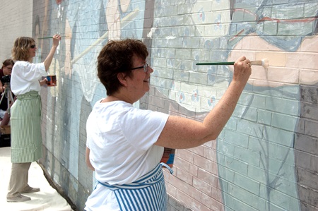 Conservator, Rika Smith-Mcnally, applies a fresh coat of paint to the mural