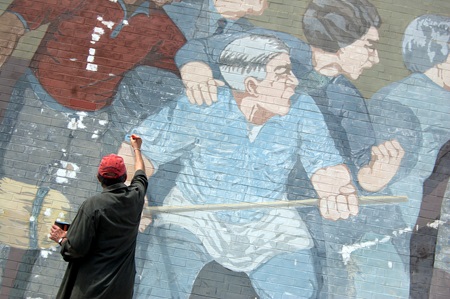 Mural artist, Bernard LaCasse, applies a fresh coat of blue paint to one of the protesters