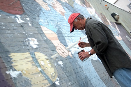 Mural artist, Bernard LaCasse, reapplies paint to his brush