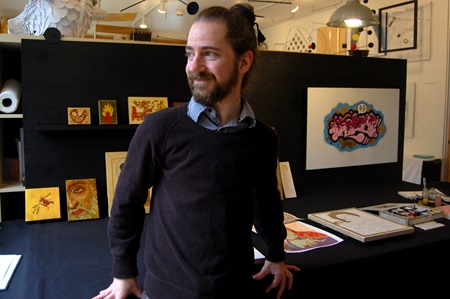 Artist Justin McIntosh poses in front of his booth at Open Studios