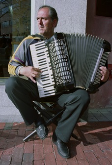 An accordion player performs on a street in Cambridge.