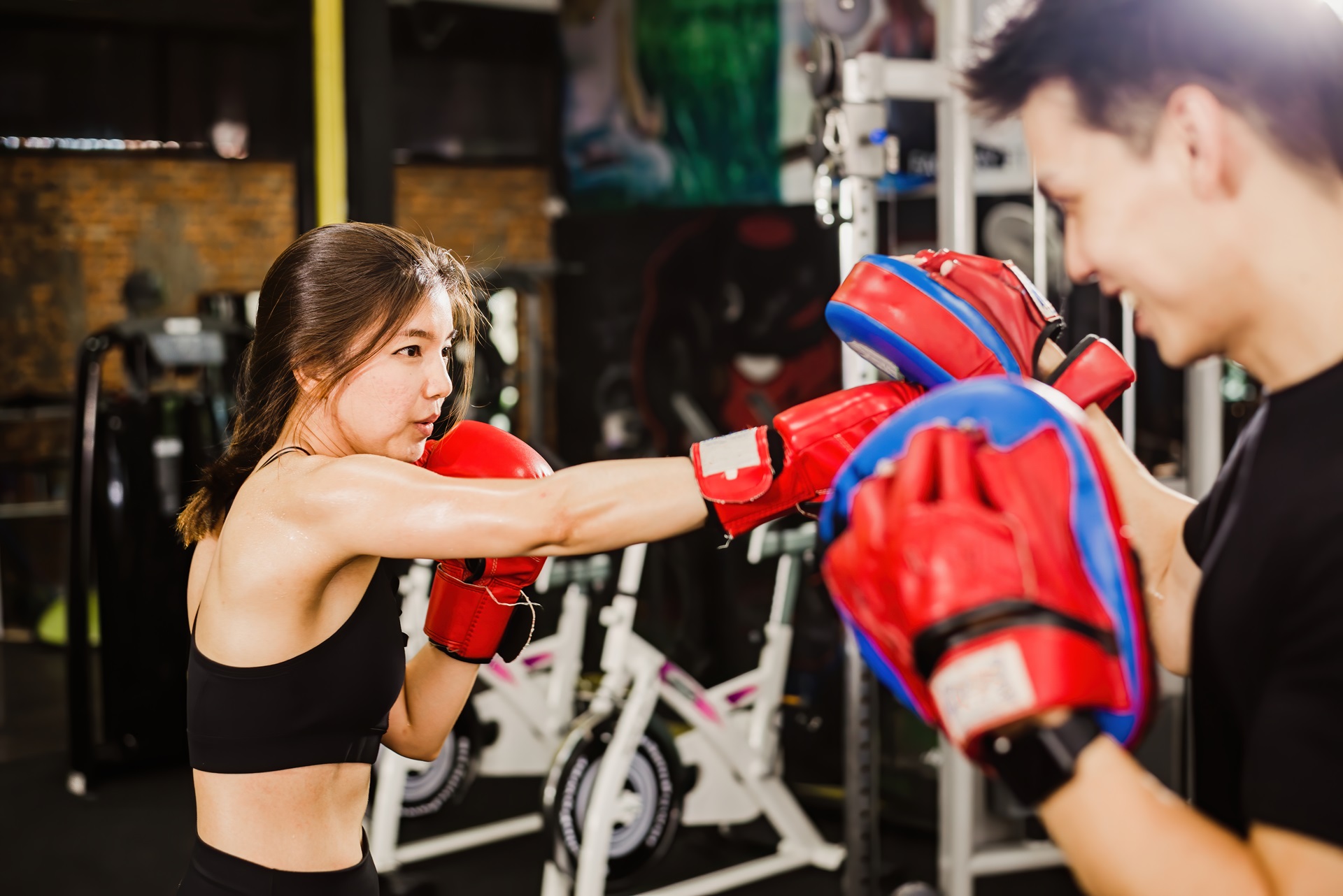 A woman and her personal trainer practicing boxing