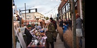 Person in green jacket looks at stationery at an outdoor market in winter in daylight