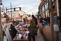 Person in green jacket looks at stationery at an outdoor market in winter in daylight