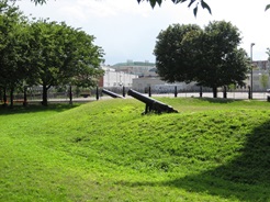 Grassy hill on a sunny day with trees and cannon sculptures