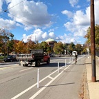 Photograph with three car lanes and a red truck on the left, flexible dividers in the center, and a bike lane with a cyclist riding their bike on the right