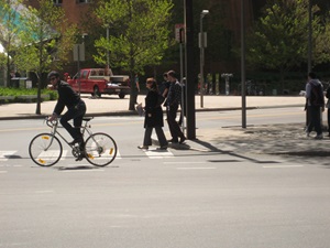 A bicylist and pedestrians move down Main Street past MIT's Stata Center in Kendall Square