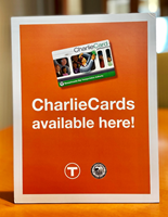 Orange sign with white border, charlieCard sits in center, text reads CharlieCards Available here, MBTA logo and City seal are at the bottom