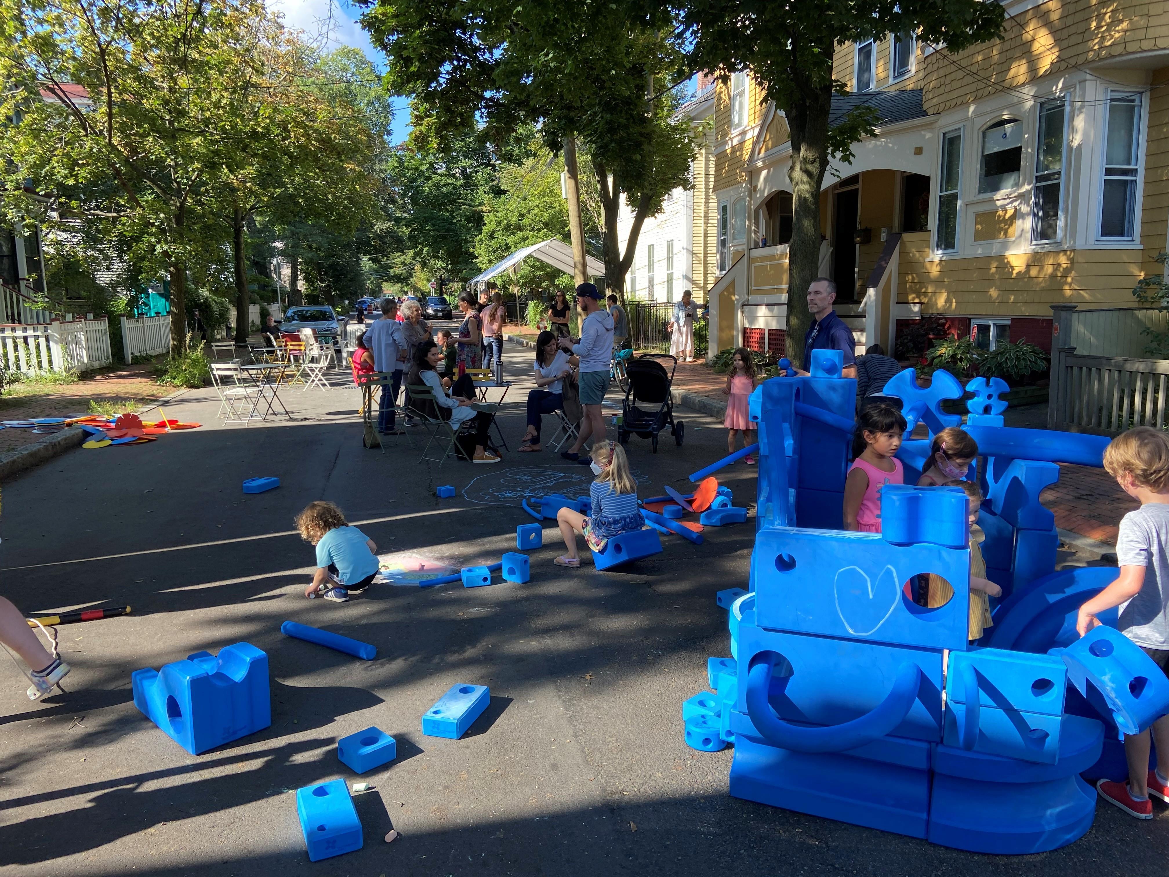 children playing with blue blocks on a sunny residential street