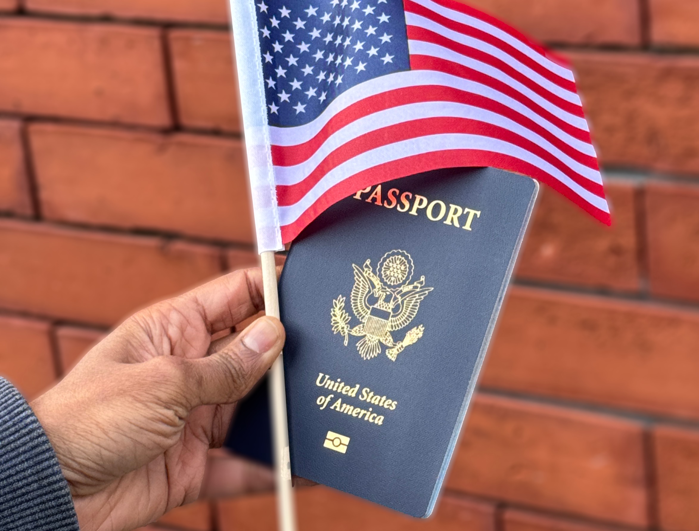 A hand holding a United States flag and passport