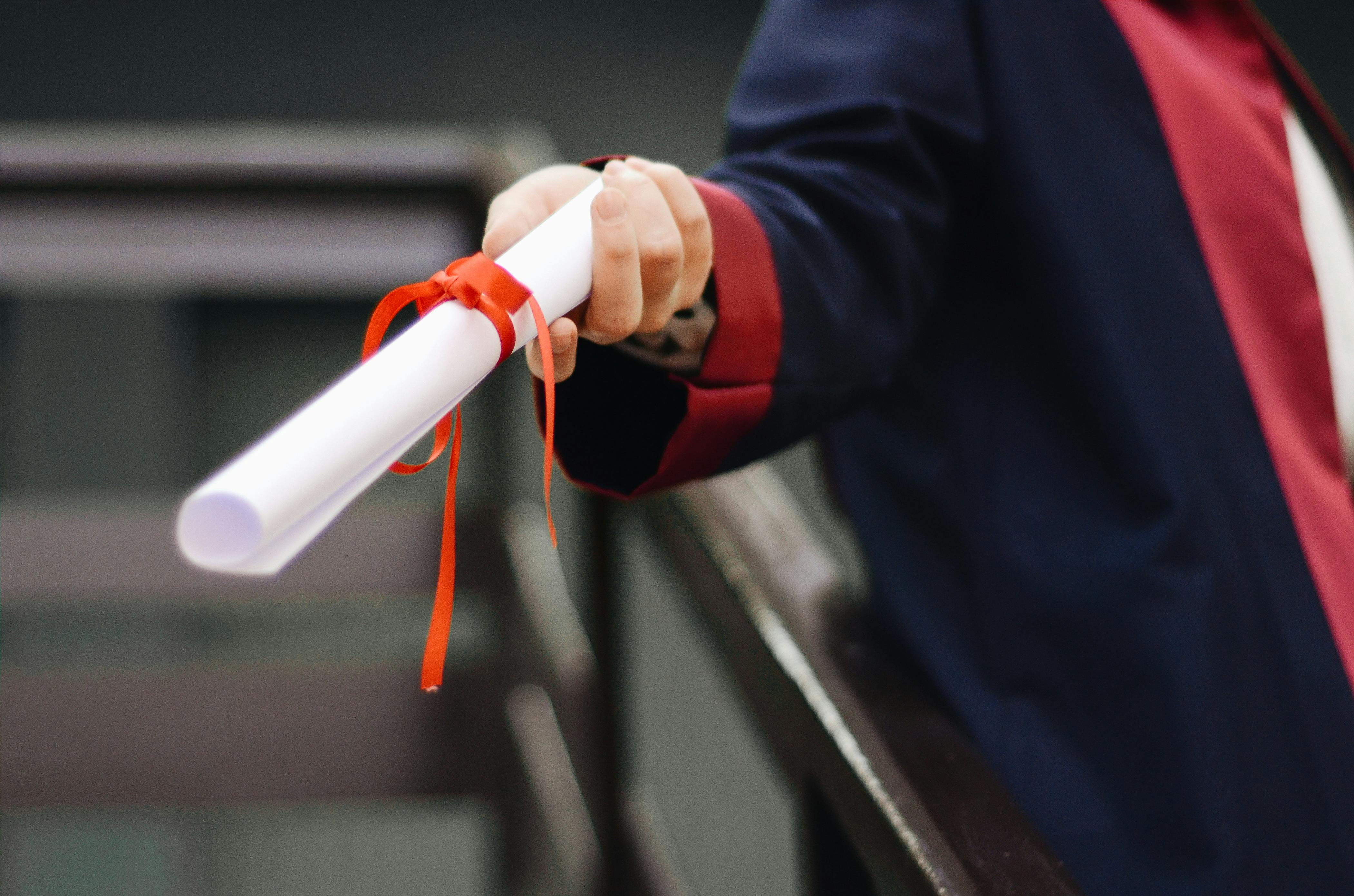 A person holds a rolled diploma in their hand