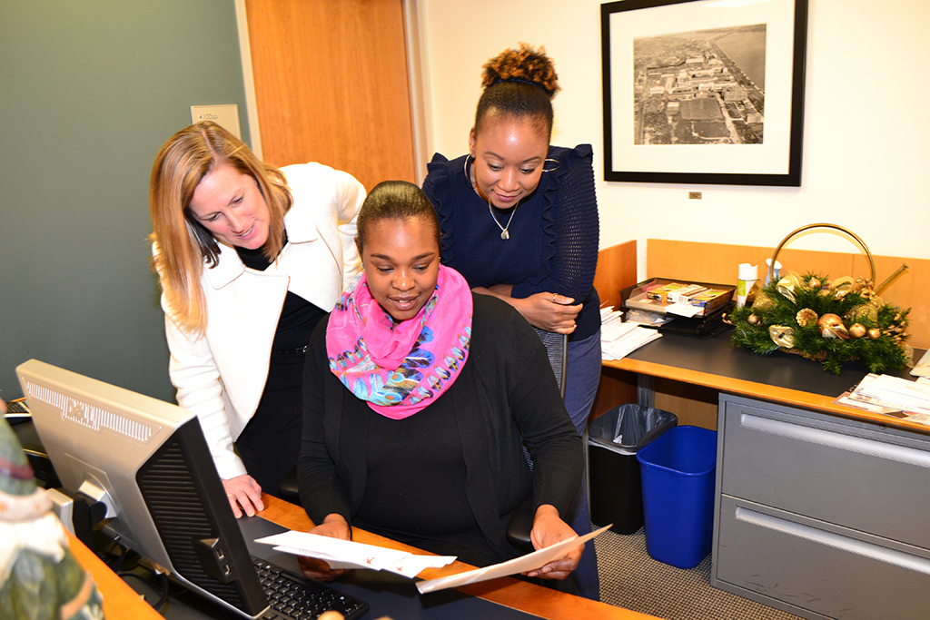 three women review documents at an office