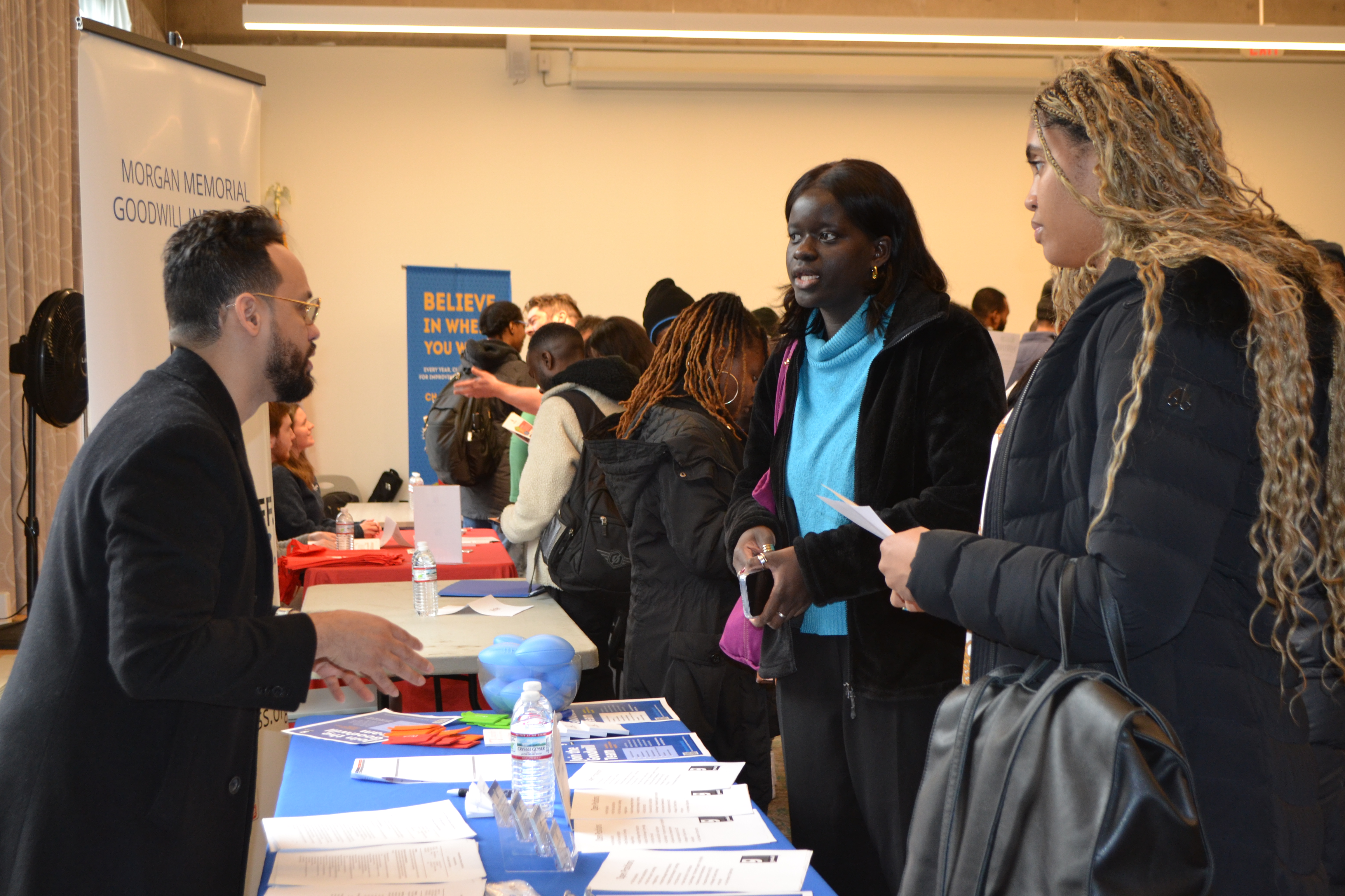 two women speak to an employer representative at an OWD job fair