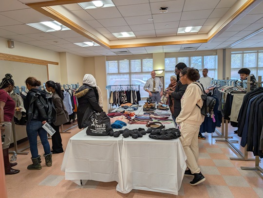 Adults browse clothing items at a pop up thrift store