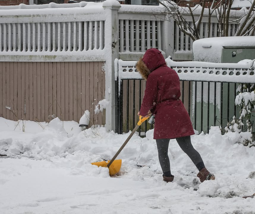 A person shovels the sidewalk after a storm