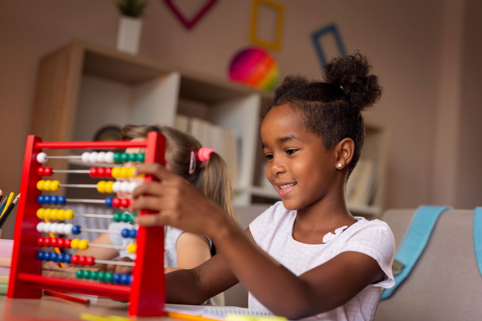 A young child plays with an abacus in a classroom
