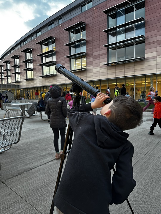 a young boy peers through a telescope during Community Astronomy Night