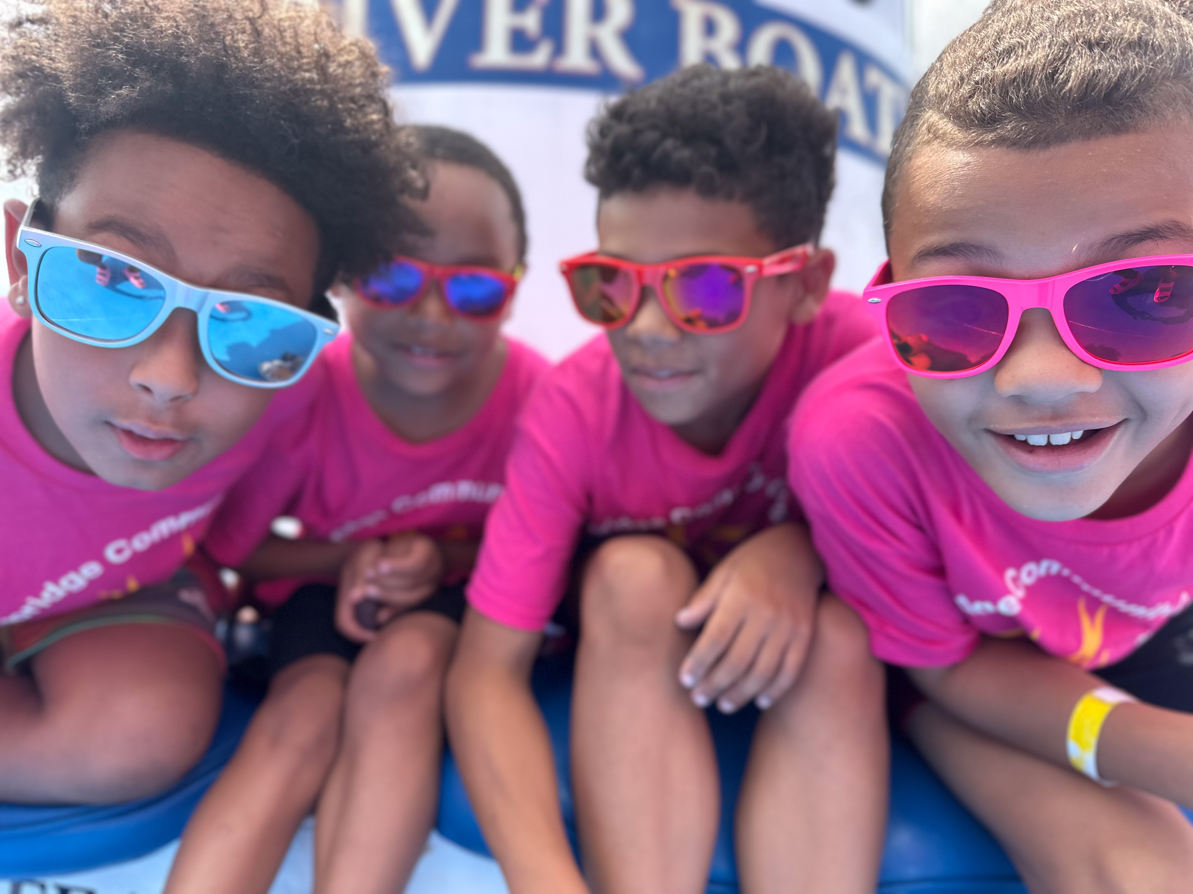 a group of young boys wearing sunglasses look into the camera