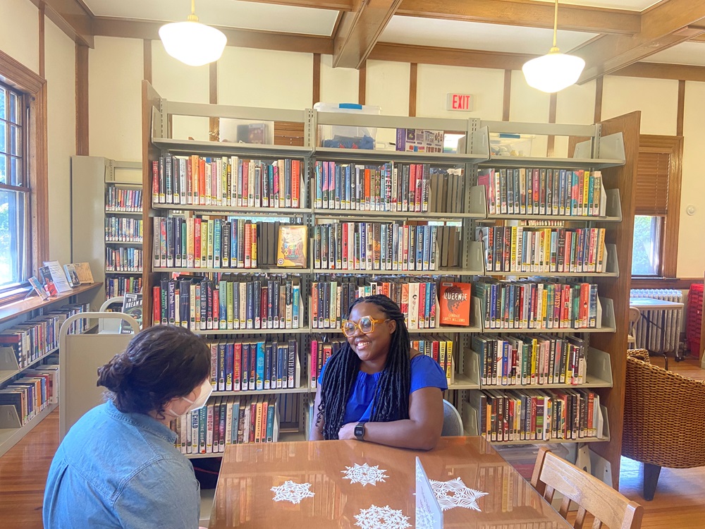 A social worker talking to a resident at a table in the Cambridge Public Library.