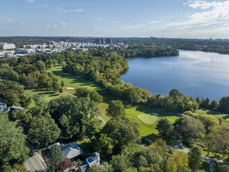 An aerial view of the golf course, green trees, and Fresh Pond.
