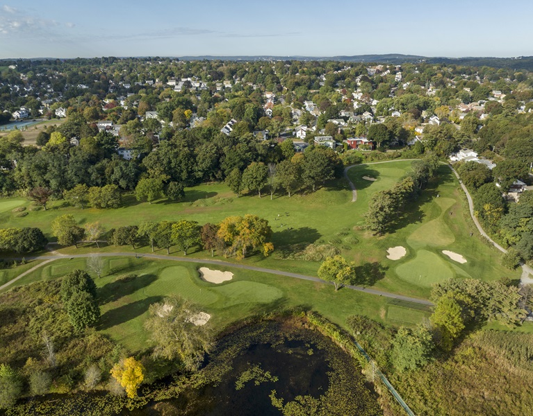 An aerial view of the golf course and the houses and trees around it.