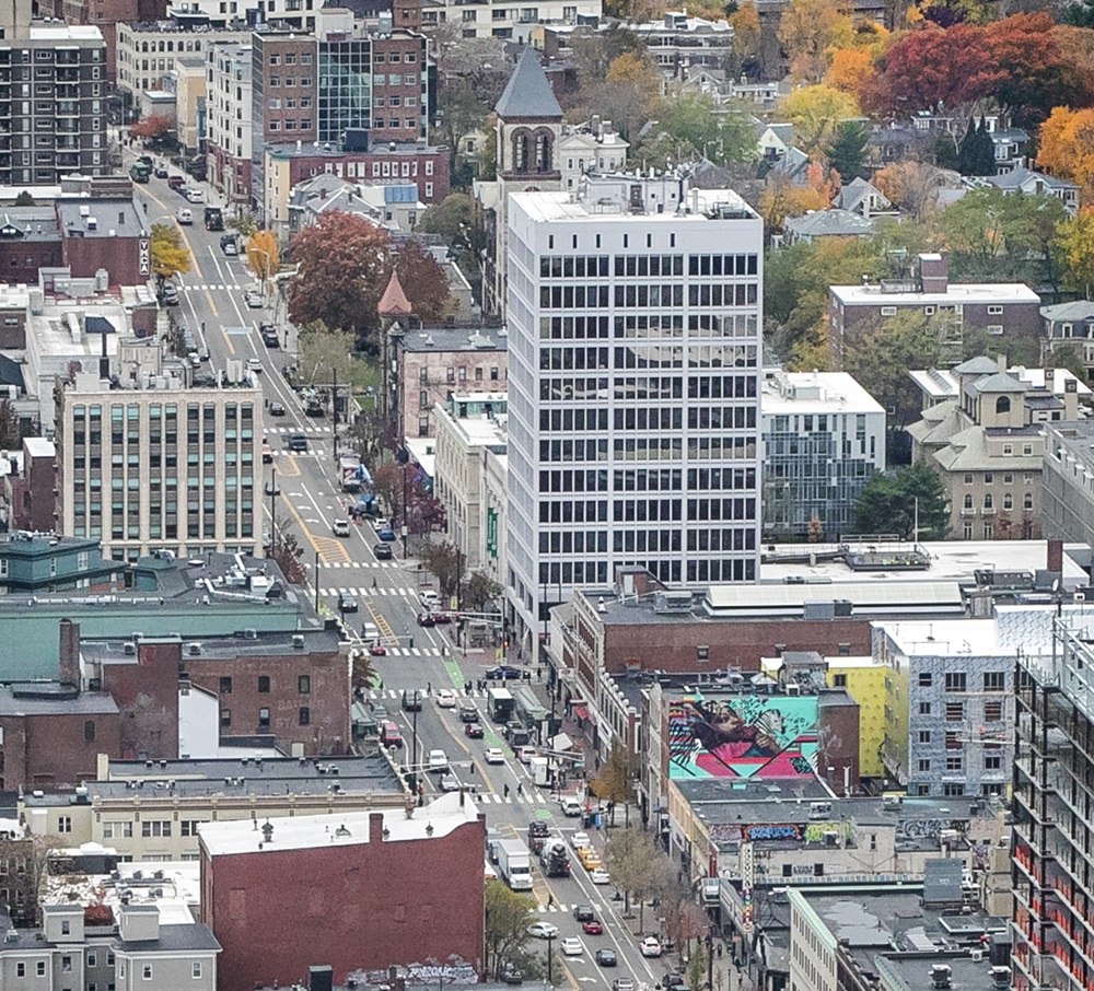 Aerial view of Central Square neighborhood with multi‑story buildings, a busy intersection, and autumn-colored trees.