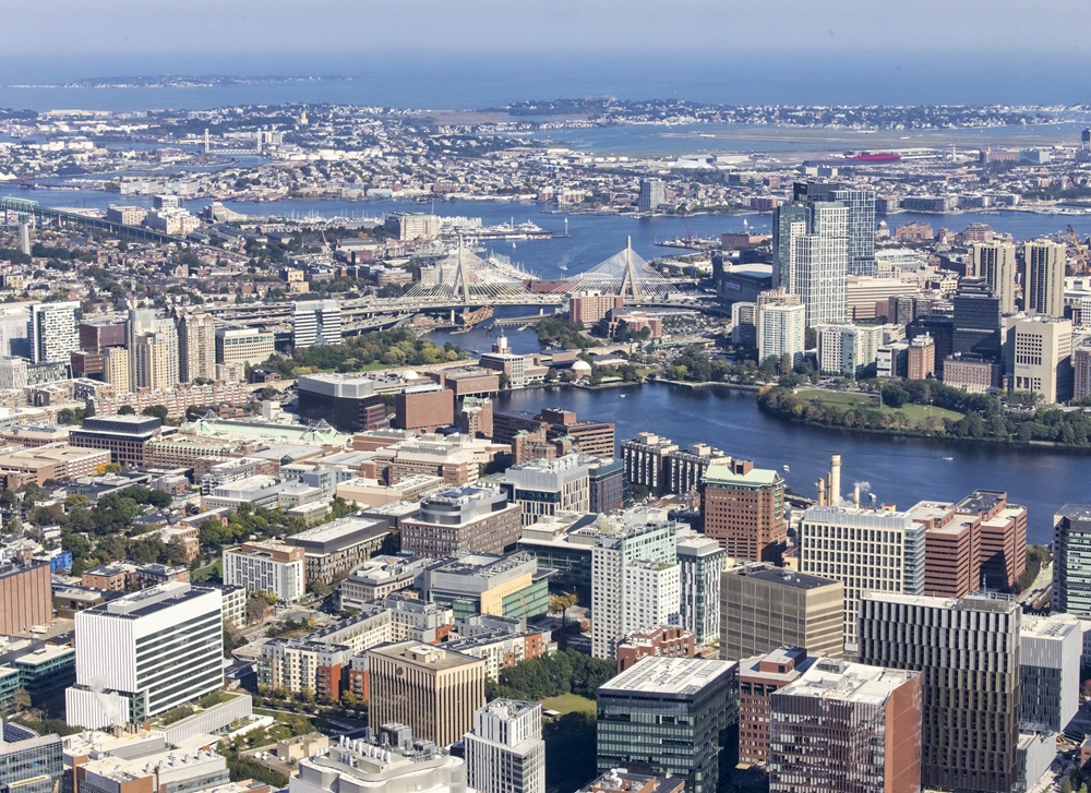 Aerial view of Kendall Square with modern buildings, roads, and green spaces near the river.