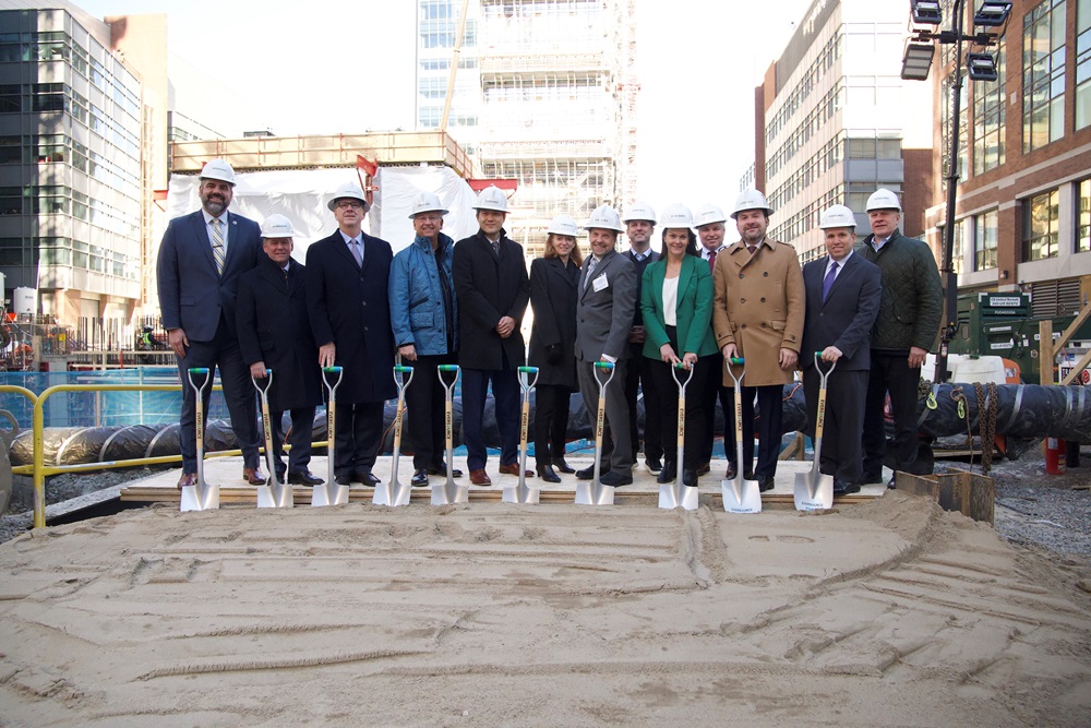Executives from the City of Cambridge, Eversource, and elected officials at a groundbreaking ceremony holding shovels with a construction site in the background.