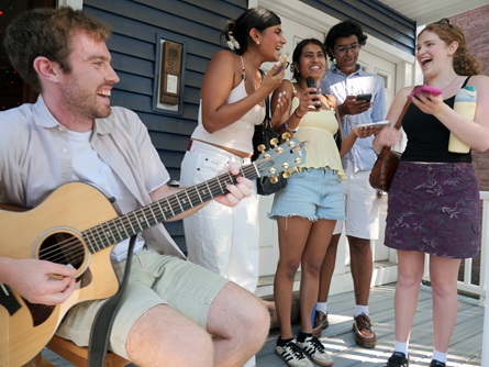 Audience members sing with Tom Dillon (left) for his live karaoke on Pearl Street during the 2026 Cambridge Porchfest.