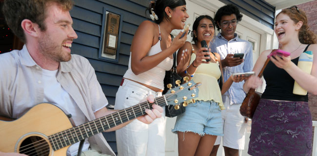 Audience members sing with Tom Dillon (left) for his live karaoke on Pearl Street during the 2026 Cambridge Porchfest.
