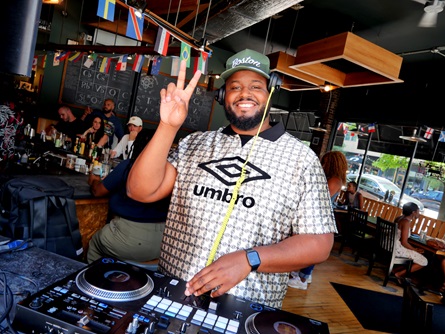 Big Bear of the Maji Mazuri collective djs at Miracle of Science on Massachusetts Avenue during the 2026 Cambridge Porchfest.