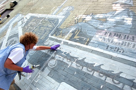 A conservator repairs cracks in the brick of the mural