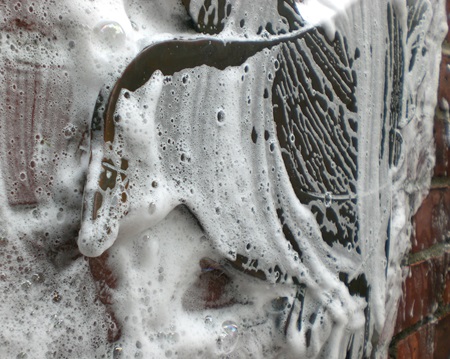Close-up photograph of a bronze sculpture getting washed.