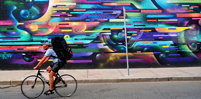 Bicyclist riding in front of Vyal "Vyal One" Reyes mural on Green Street side of the Middle East Night Club in Cambridge's Central Square.