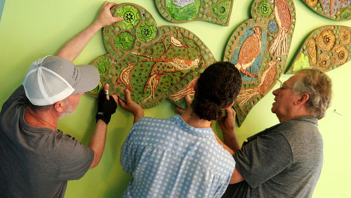 Inside the Cambridge Housing Authority's Millers River Apartments in July, Craig Uram (from left) and Oussama Ouadani of Cambridge Arts and conservator Greg Curci reinstalled mosaics created by Lilli Ann Rosenberg for the residences in 1979.