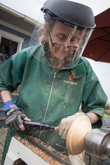 A craftswoman demonstrates her skills as a woodturner by carving a wooden bowl during Cambridge Open Studios.