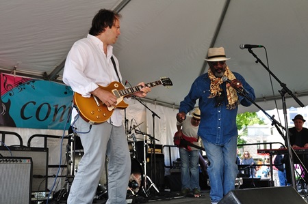 A band performs at Cambridge River Festival, shown are a guitarist and lead singer.