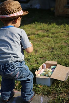 A young attendee investigates a box full of sidewalk chalk at River Festival