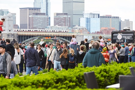 A crowd walking down the street with a view of the Boston skyline