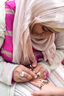 A henna artist embellishes a River Festival goer's hand.