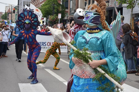 Behind the Mask Studio (foreground) and Fine Art Superheroes process down Massachusetts Avenue during the Mermaid Promenade at the 2019 Cambridge Arts River Festival.