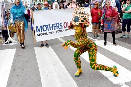 Fine Art Superheroes and Mothers Out Front process down Massachusetts Avenue during the Mermaid Promenade at the 2019 Cambridge Arts River Festival.