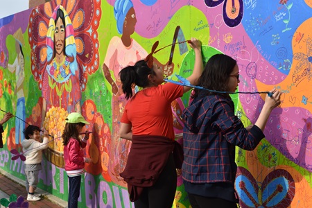 People add to Liz LaManche’s interactive mural about women doing small scale farming at the 2019 Cambridge Arts River Festival.