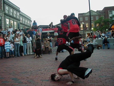 A breakdance crew performs for a public crowd in the middle of Harvard Square in Cambridge.