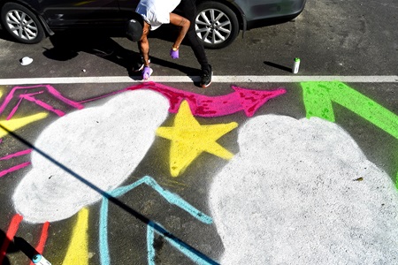 Lamar Atkins of Yurp Nation paints on the street during the Community Art Center’s Port Arts Festival in Cambridge, June 15, 2018.