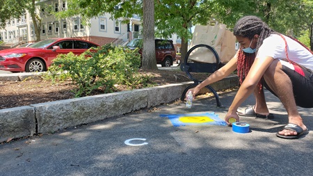 A member of the Cambridge Arts Public Art Youth Council chalk-paints hoof prints for their 2020 project 