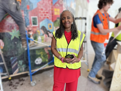 Portrait of artist Ekua Holmes in front of her mosaic during installation of “You Belong Here.” Photo by Cambridge Arts.
