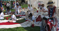 Participants in one of artist Allison Smith's workshops stitch into white fabric